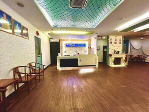 A reception area with a wooden floor, a reception desk, and a wall-mounted sign.