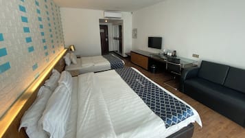 A hotel room with two beds, a desk with a computer, a TV, and a couch.