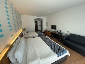 A hotel room with two beds, a desk with a computer, a TV, and a couch.