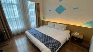 Una camera d'albergo con un letto grande, un comodino con il telefono e una parete con motivo geometrico.