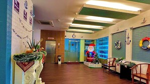Una hall d'albergo con pavimento in legno, una reception, un albero di Natale e una decorazione con Babbo Natale.