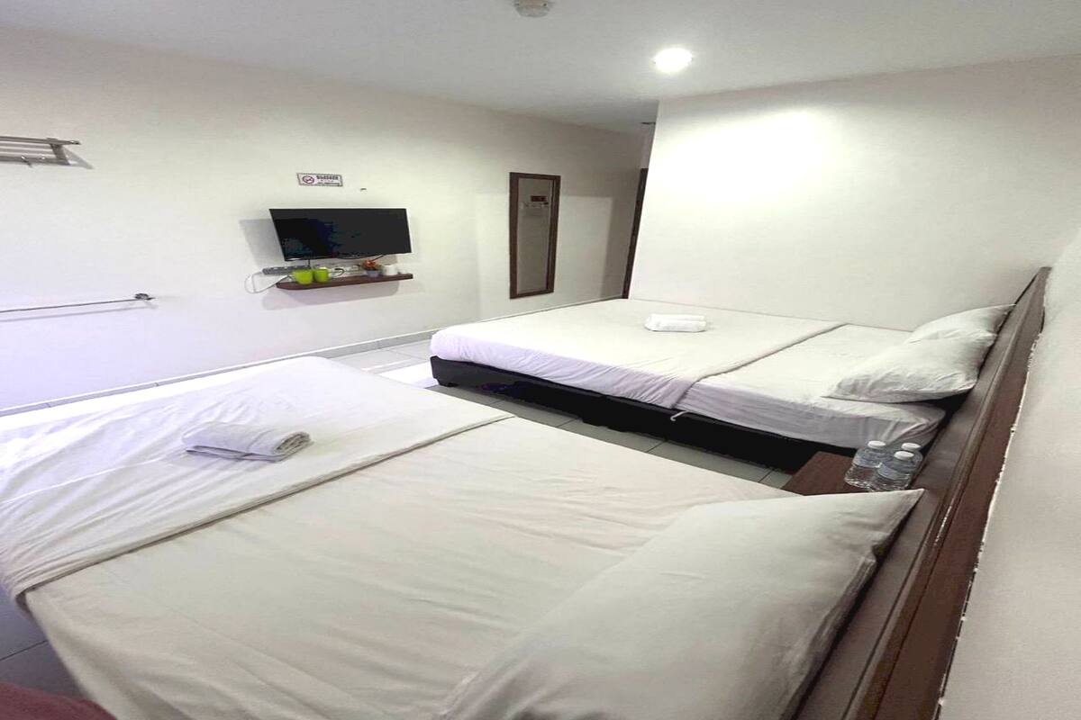 Een hotelkamer met twee bedden, een televisie en een spiegel.