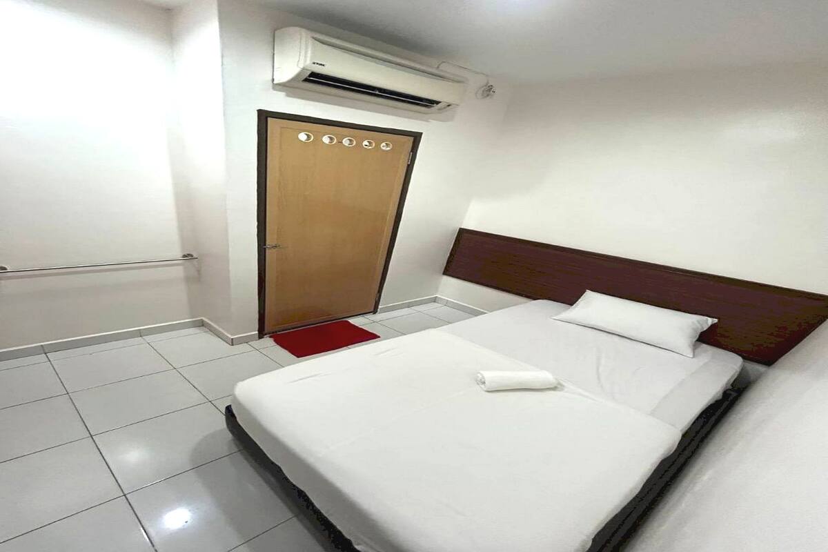 Een hotelkamer met een bed, een houten deur, een airconditioner en een rood kleed.