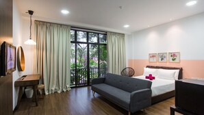 Ein modernes Hotelzimmer mit großem Fenster, einer Couch, einem Bett, einem Schreibtisch und einem Fernseher.