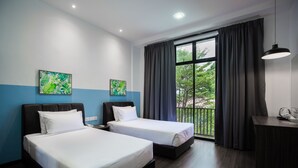 Ein Hotelzimmer mit zwei Betten, einem Schreibtisch und einem Balkon mit Vorhängen.