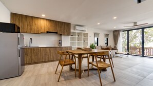A modern kitchen with wooden cabinets, a built-in oven, and a dining area with a wooden table and chairs.