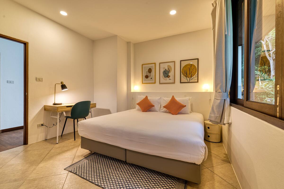 Une chambre à coucher avec un lit, un bureau, une chaise et une œuvre d’art accrochée au mur.
