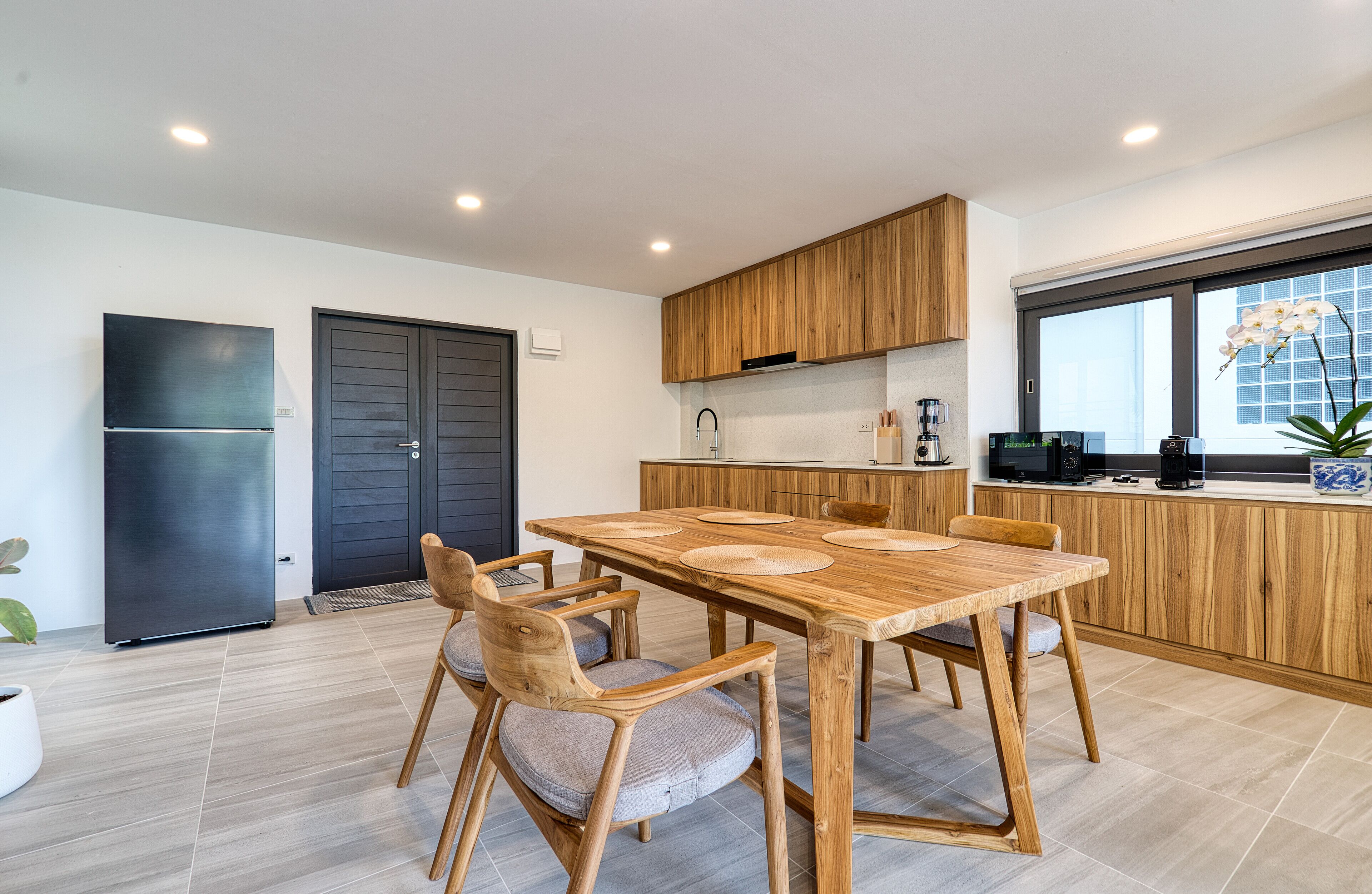 A modern kitchen with wooden cabinets, a large dining table, and a built-in oven.