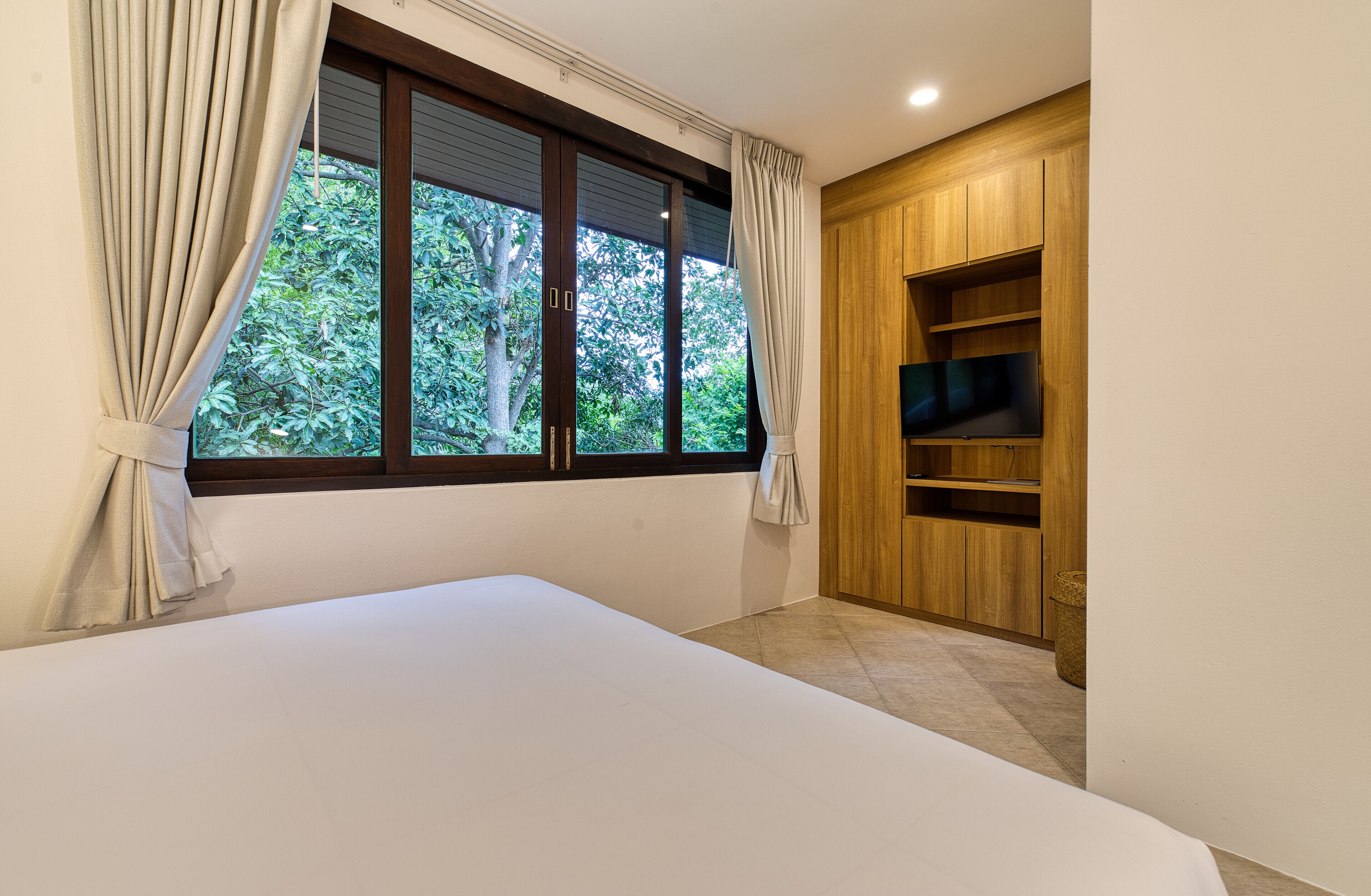 Un dormitorio con una cama grande, una ventana con cortinas y una estantería empotrada de madera.
