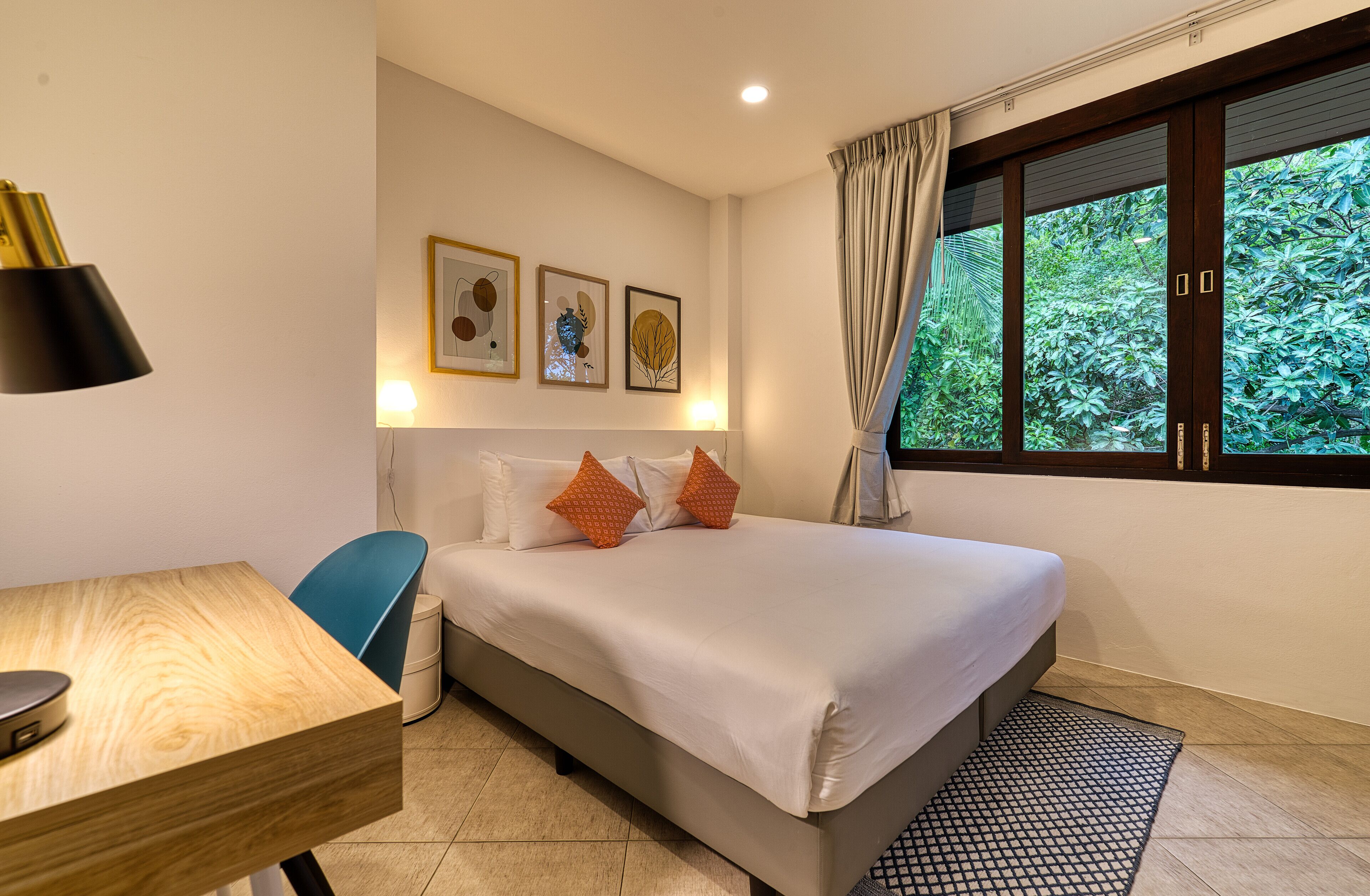 A hotel room with a bed, a desk, and a window with curtains.