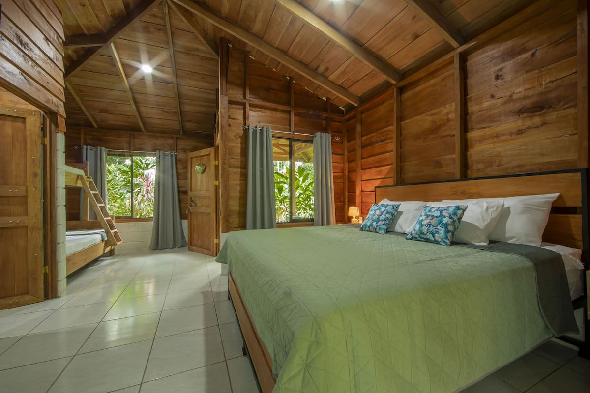 A wooden cabin bedroom with a bed, curtains, and a window.