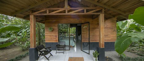 A wooden cabin with a covered porch, two benches, and a small potted plant.
