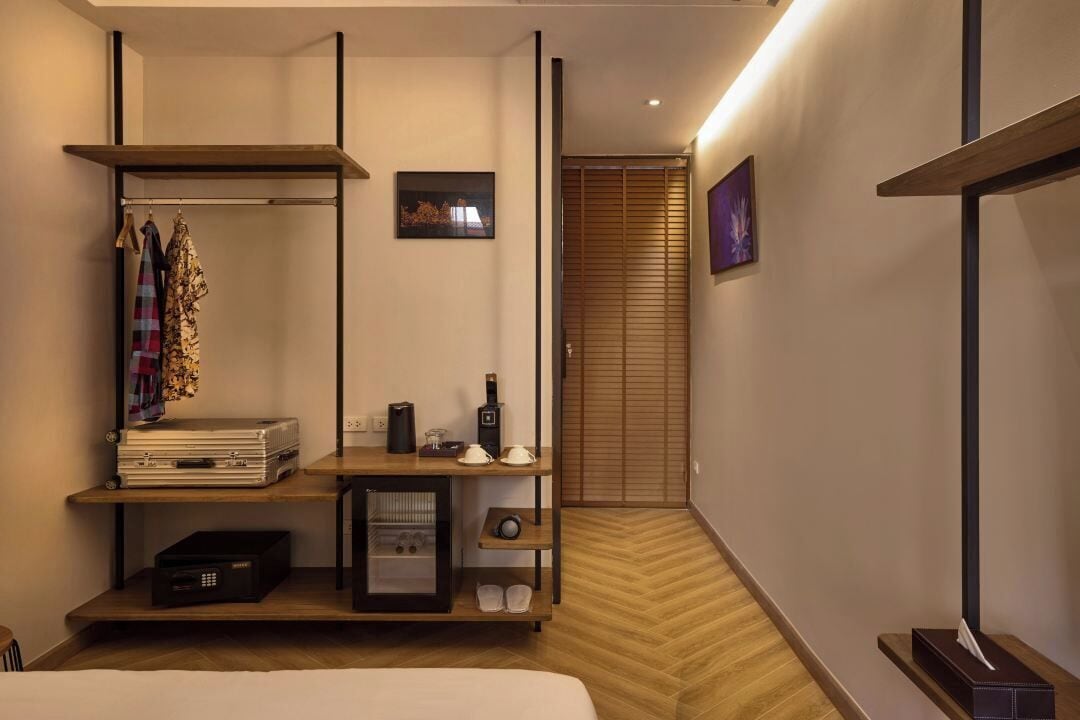 Une chambre d’hôtel comprenant un lit, un bureau avec un ordinateur, une étagère avec des vêtements et une armoire.