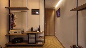 Une chambre d’hôtel comprenant un lit, un bureau avec un ordinateur, une étagère avec des vêtements et une armoire.