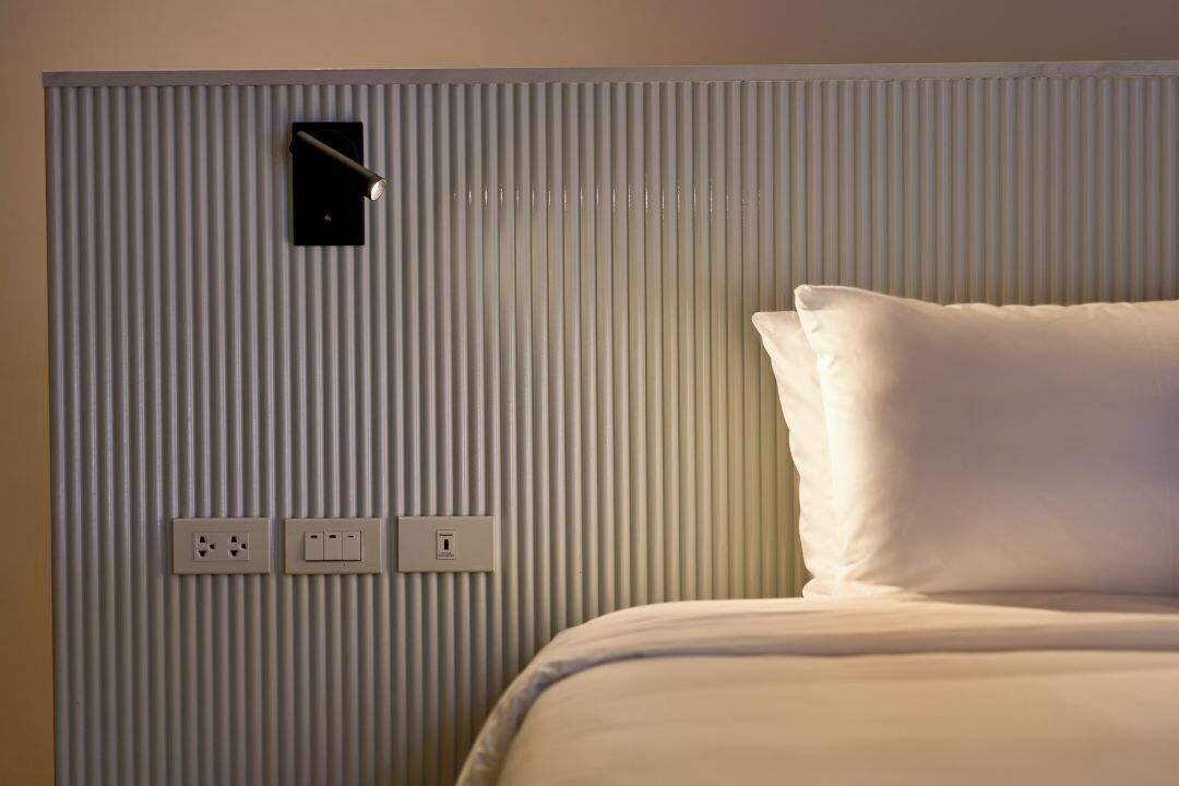 Ein Hotelzimmer mit einem Bett, einer Wandleuchte und Steckdosen.