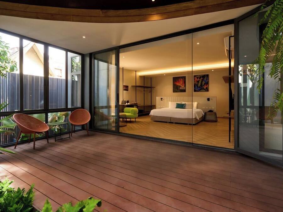 Un dormitorio moderno con una cama grande, un ventanal de vidrio que da a un balcón y vistas al exterior.