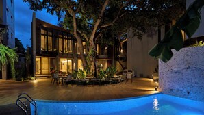 A modern building with a pool and outdoor seating area. - Red Door (Bangkok)