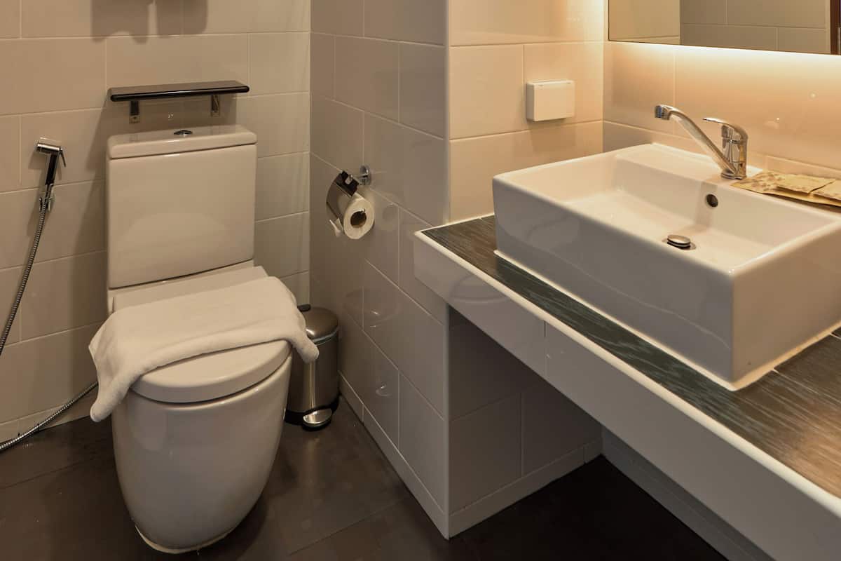A modern bathroom with a toilet, sink, and mirror.