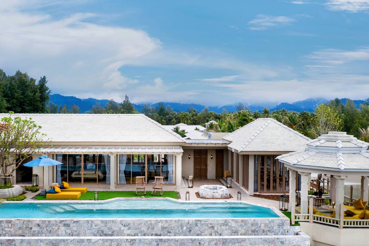 A resort with a swimming pool, outdoor seating, and a view of mountains.