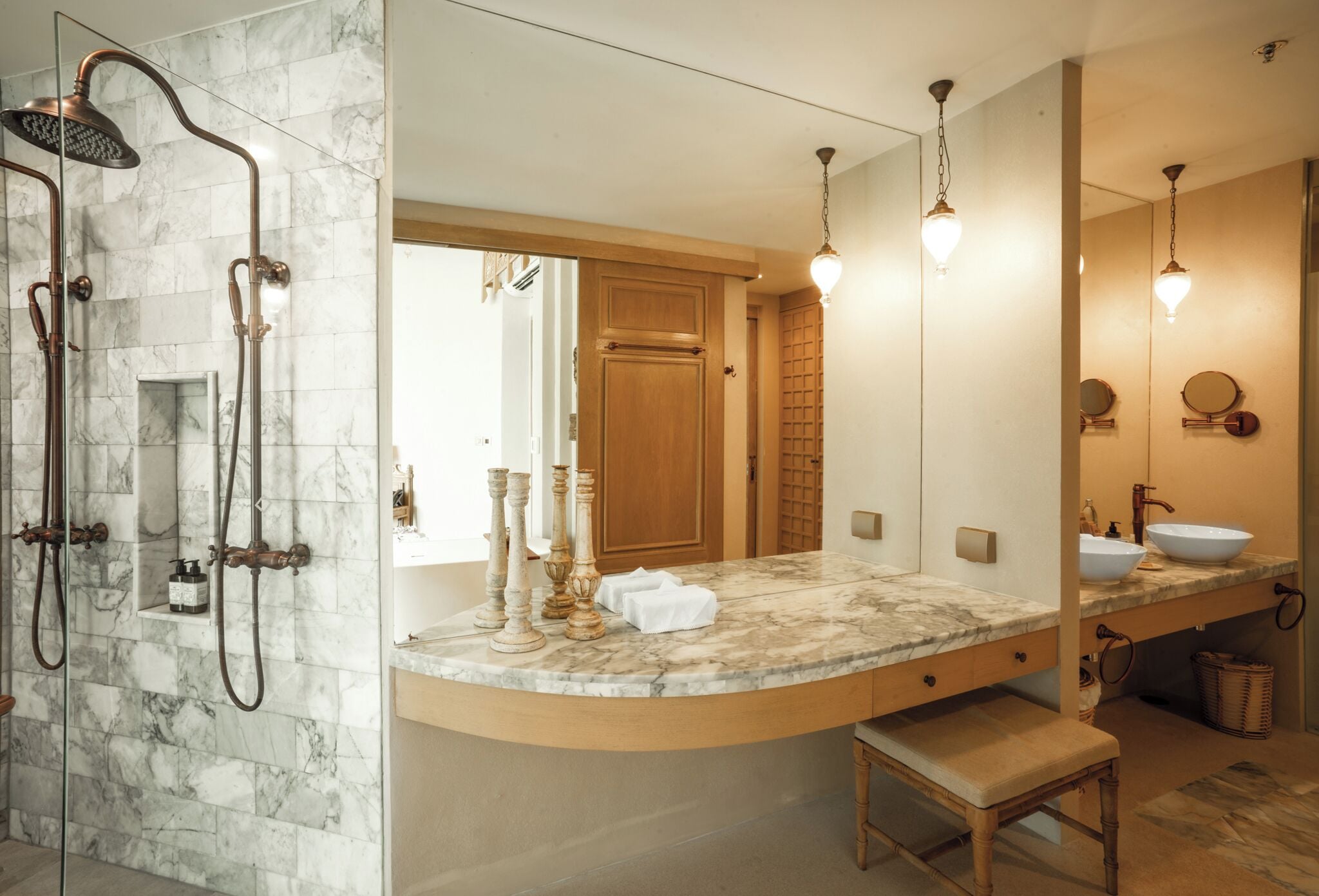 A bathroom with a shower, a vanity with a sink, a mirror, and a bench.