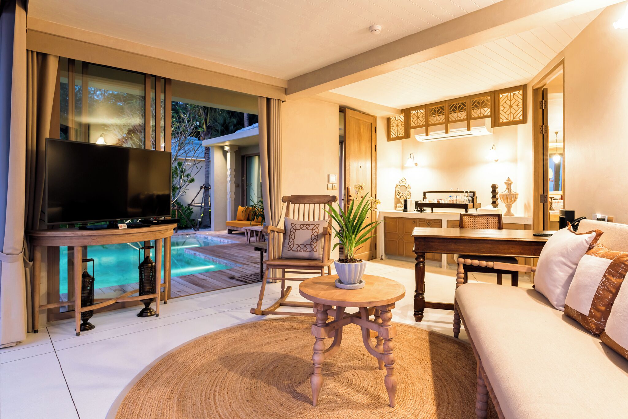 A spacious living area with a TV, seating, a dining table, and a kitchen area.