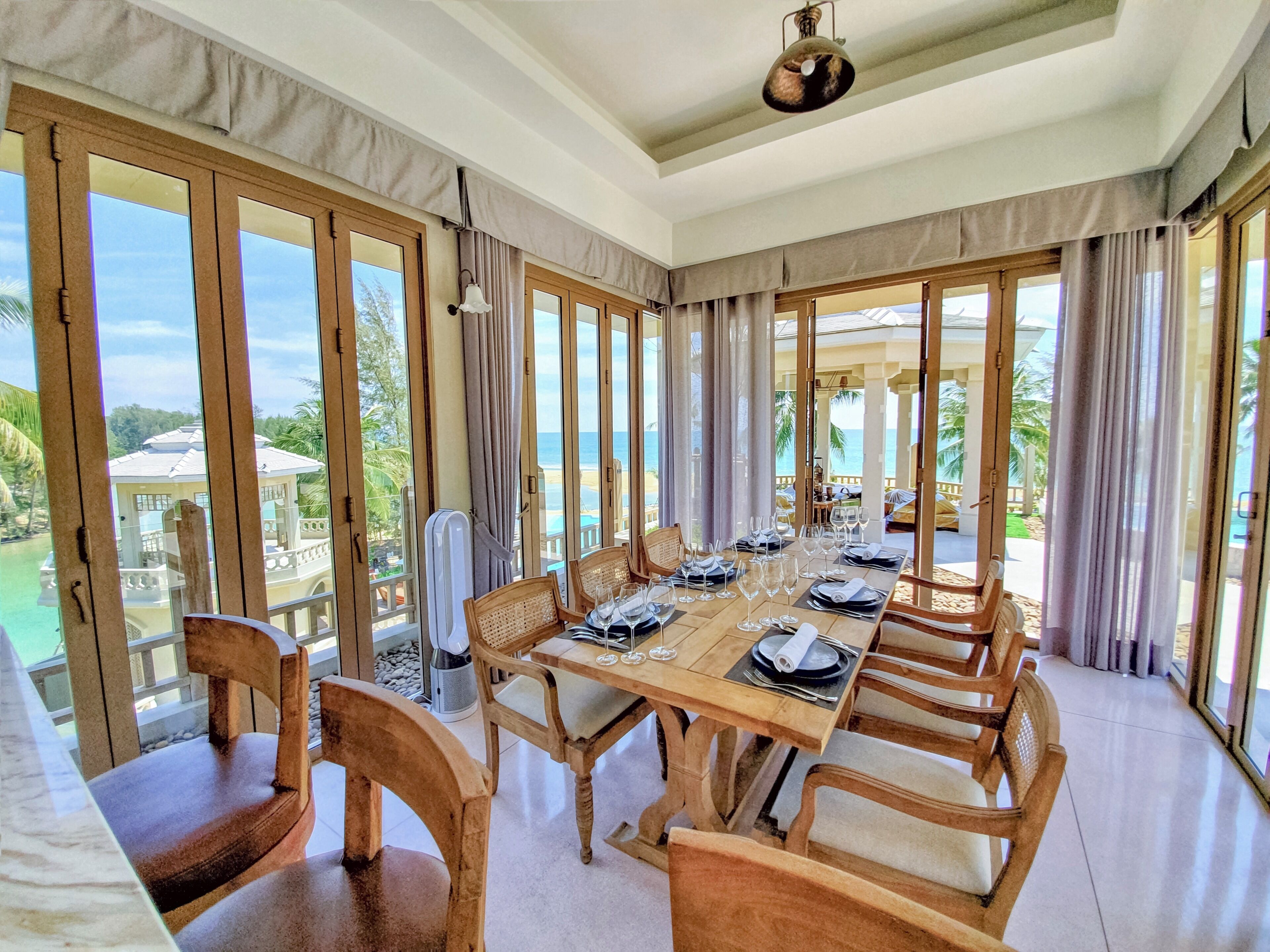 Comedor con una mesa lista para una comida, ventanas amplias y vista a la playa.
