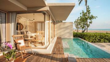 A wooden deck with a pool, outdoor furniture, and a view of the beach.