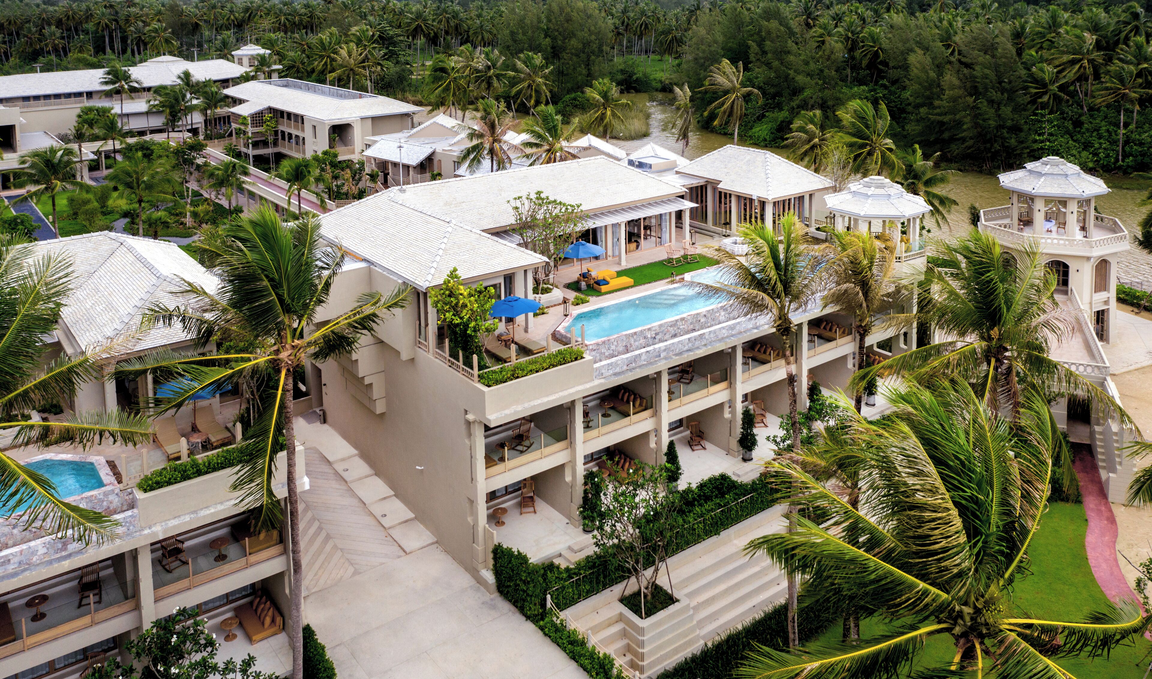 Een resort met meerdere gebouwen, een zwembad en weelderige begroeiing.