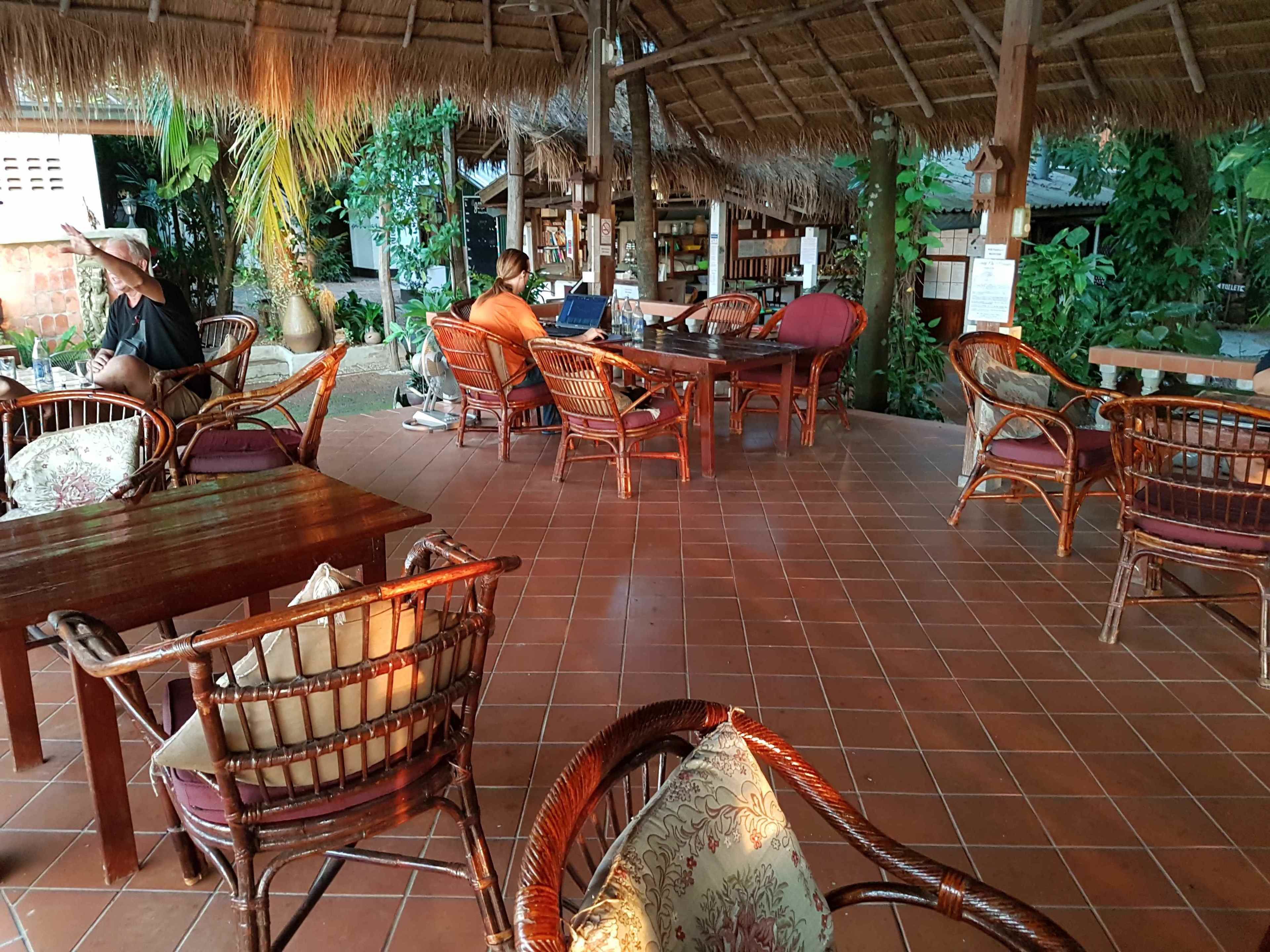 Un área de estar al aire libre con muebles de mimbre y techo de paja.