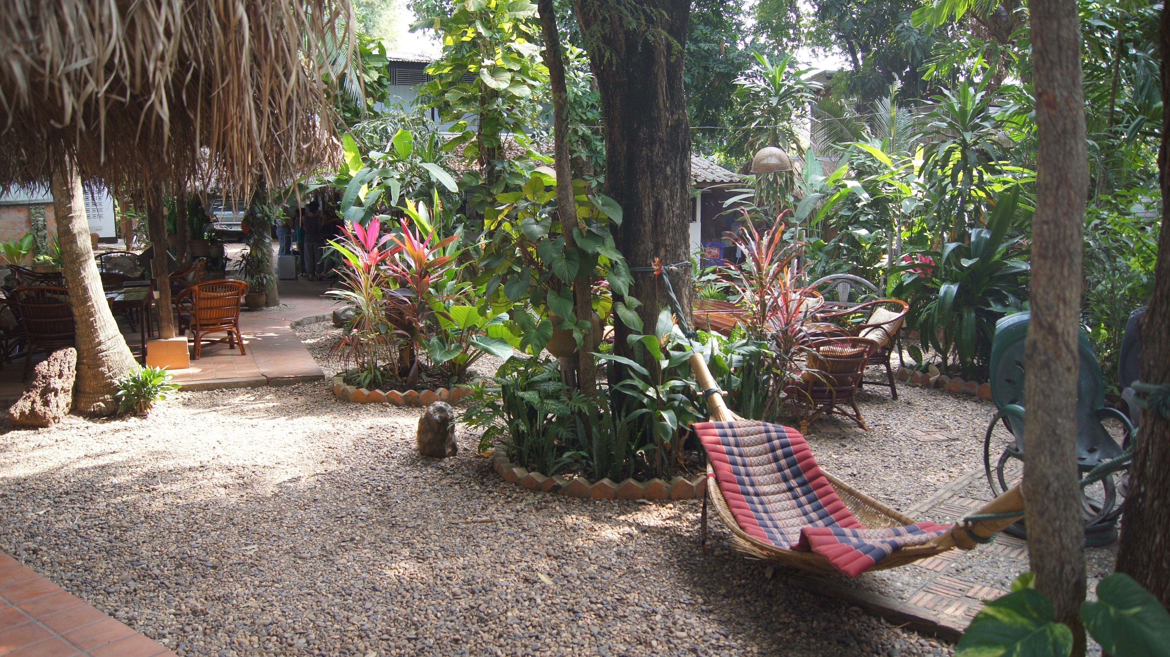 A garden area with a hammock, seating, and various plants.