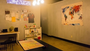 Um quarto com uma escrivaninha, cadeiras, um mapa na parede e um mapa-múndi.