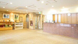 A reception area with a marble counter, a reception desk, a wall-mounted clock, and a framed picture.