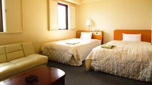 A hotel room with two beds, a sofa, a table, and a window.