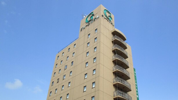 A tall, beige building with a prominent logo at the top.