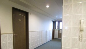 A hallway with a door marked "2110", a telephone on the right wall, and a tiled floor.