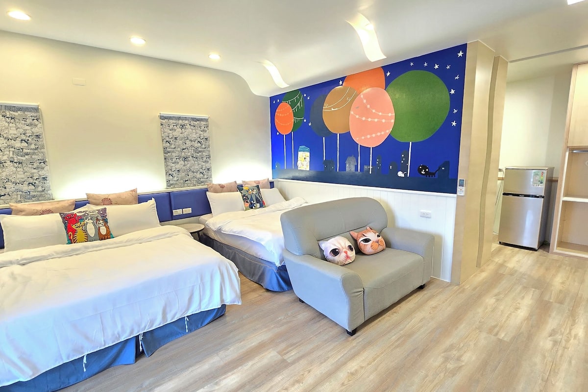 Habitación de hotel moderna con dos camas, un sofá y un mural en la pared.