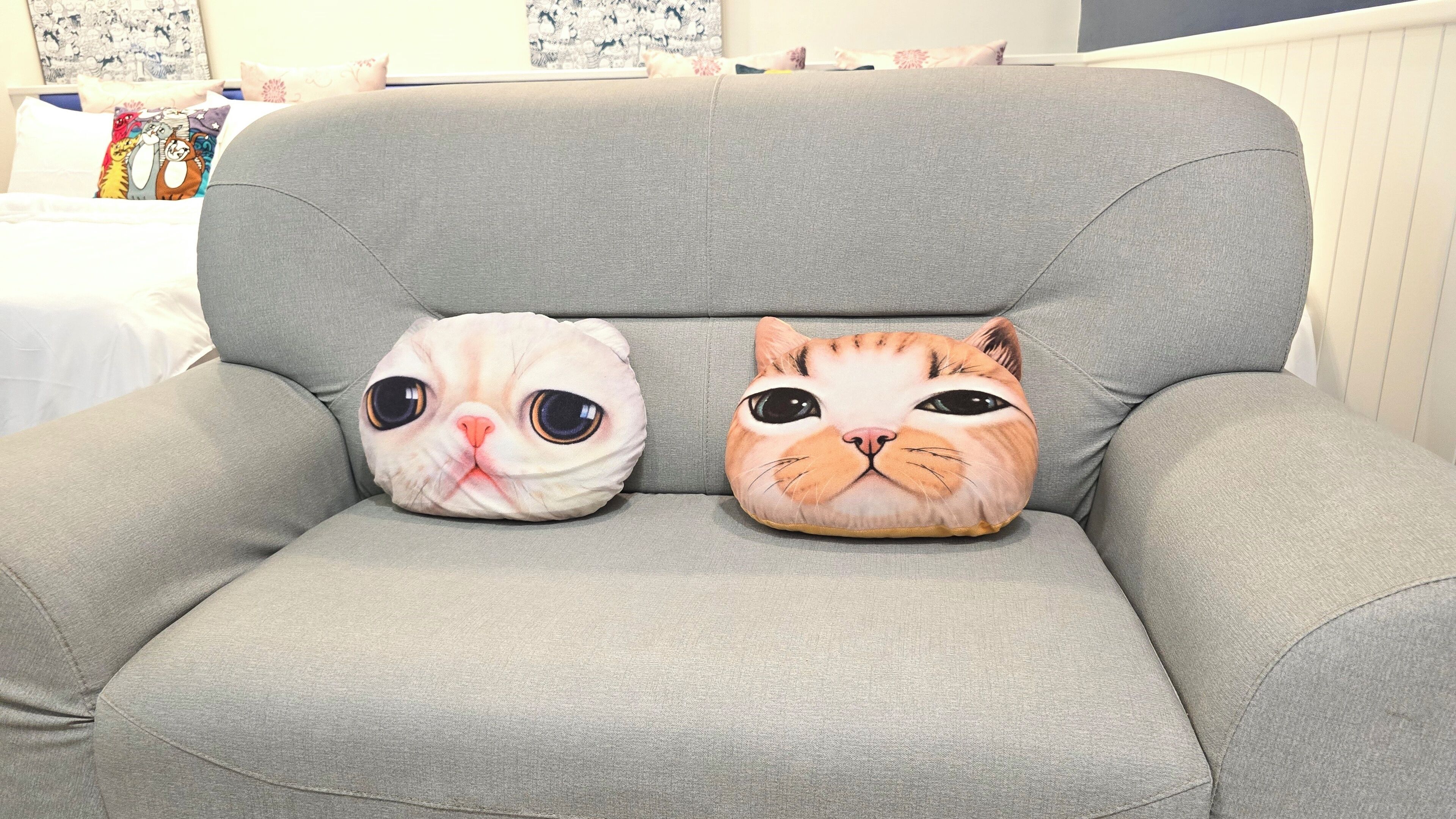 Two cat-shaped pillows on a grey sofa.