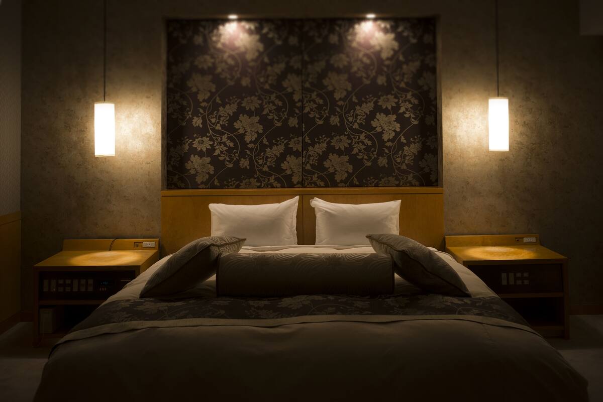 Ett hotellrum med en stor säng, två sängbord och en sänggavel med blommönster.