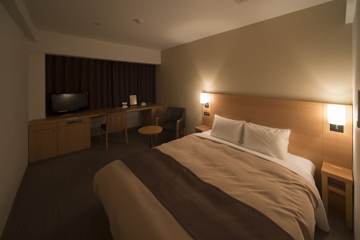 Ett hotellrum med en stor säng, ett skrivbord med en tv och två sänglampor.