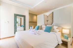 Un dormitorio amplio con una cama grande, un adorno en la pared y una mesita de noche con lámpara.