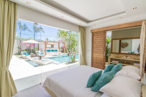 Un dormitorio con una cama grande, vistas a una piscina y un armario de madera.