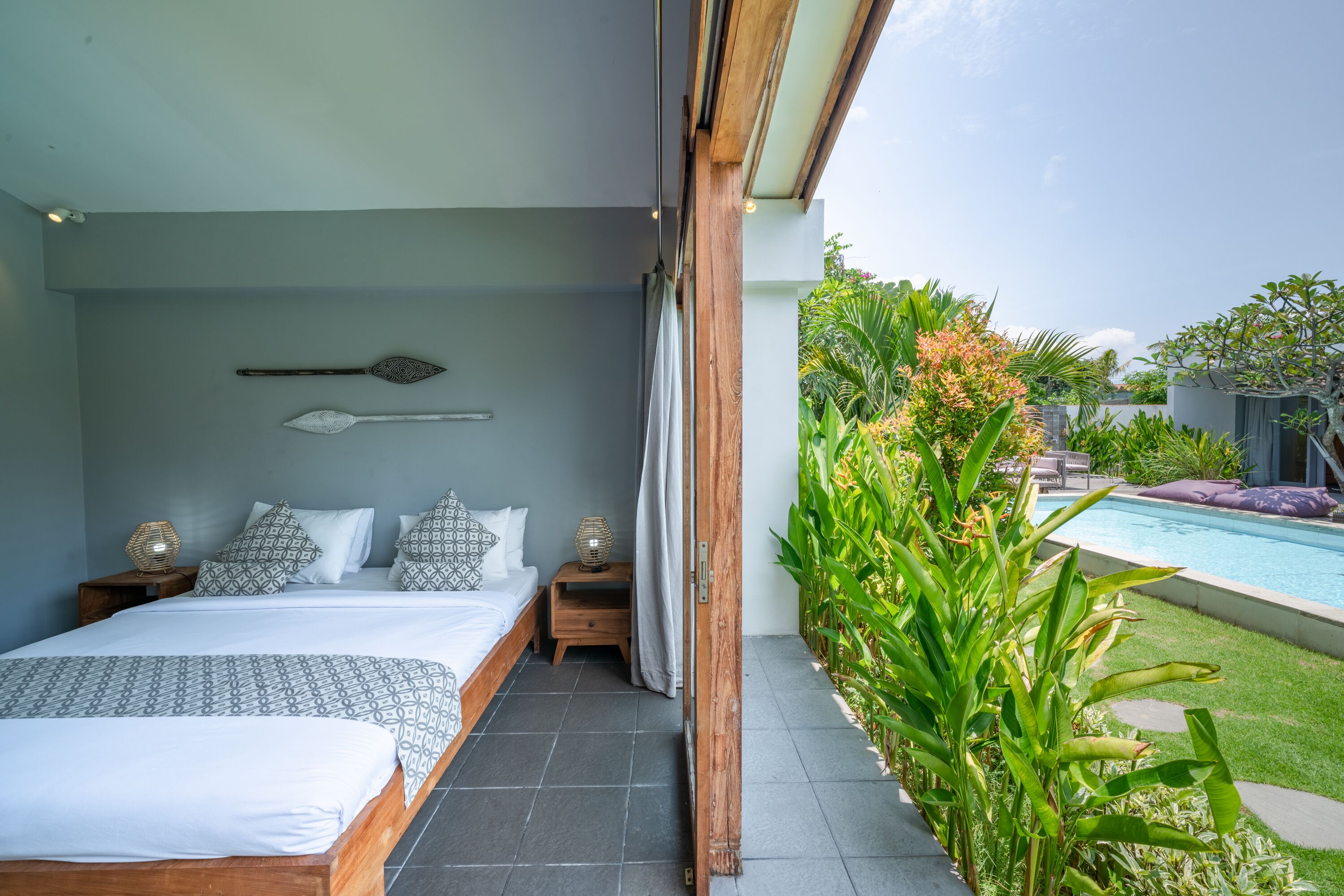 Un dormitorio con una cama grande, mesitas de noche y vistas a una piscina.