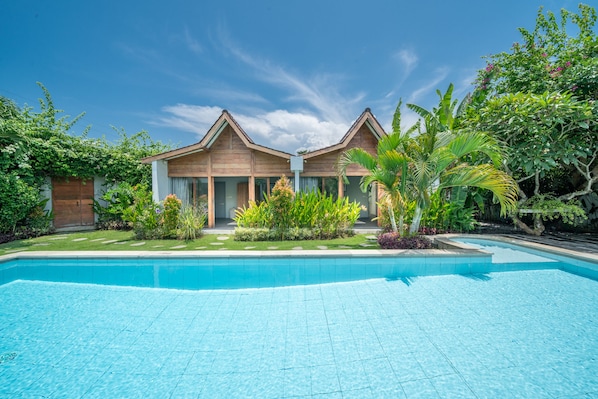 A hotel with a swimming pool, surrounded by lush greenery and tropical plants.