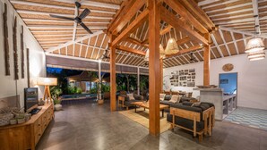 A spacious indoor area with a wooden ceiling, a pool, and a seating area with sofas and tables. - Villa Nahema (Seminyak)