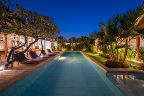 Relax by the serene pool surrounded by lush greenery and modern architecture.