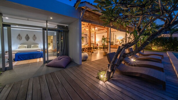 A modern house with a wooden deck, a pool, and a dining area. - Villa Nahema (Seminyak)