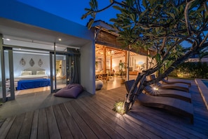 A modern house with a wooden deck, a pool, and a dining area.