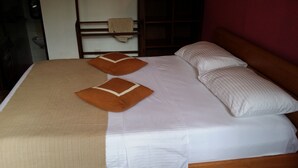 Ein Bett mit weißer und brauner Bettwäsche, zwei Kissen und einer beigen Tagesdecke.