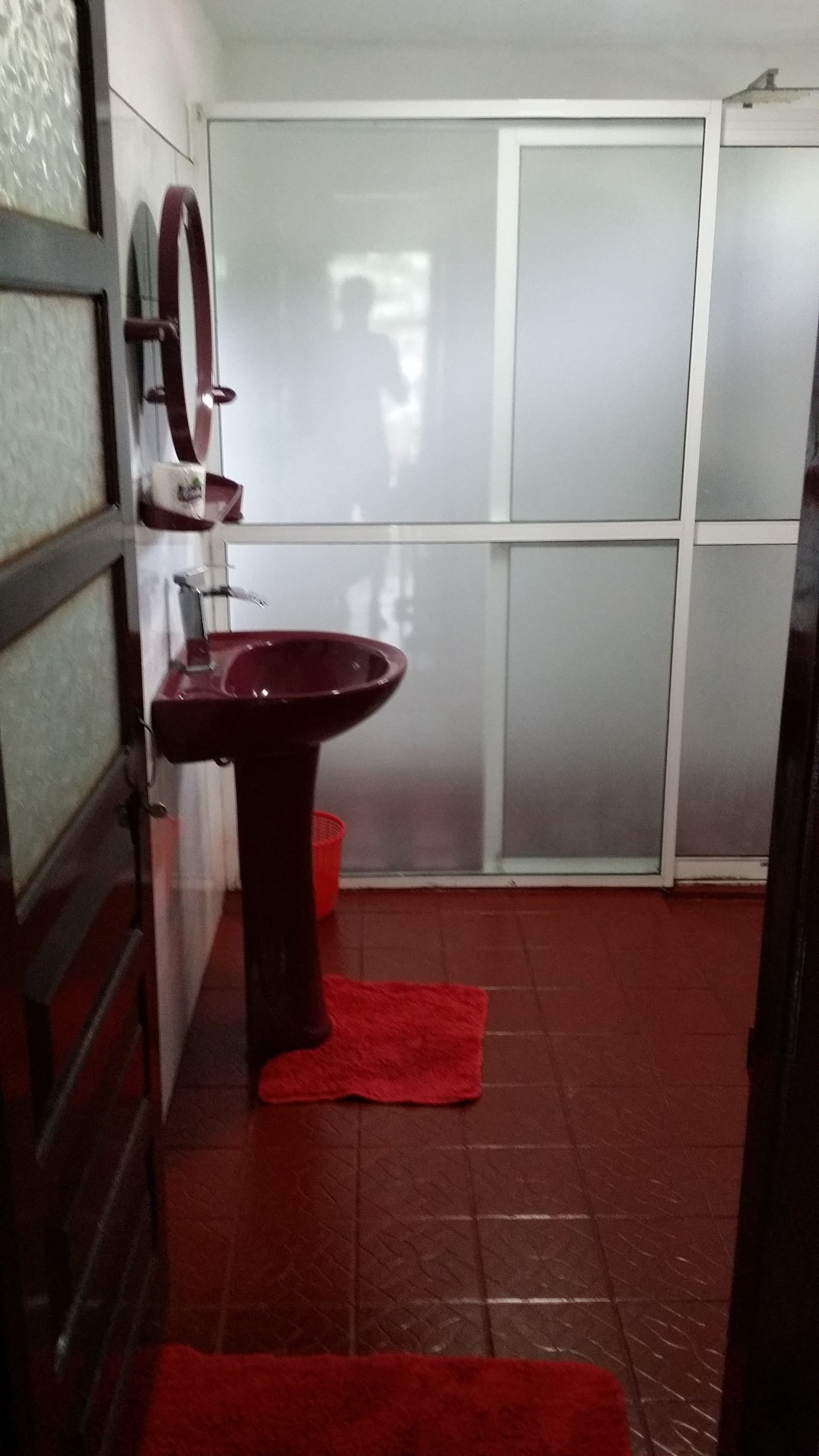 A bathroom with a red sink, a mirror, and a tiled floor.