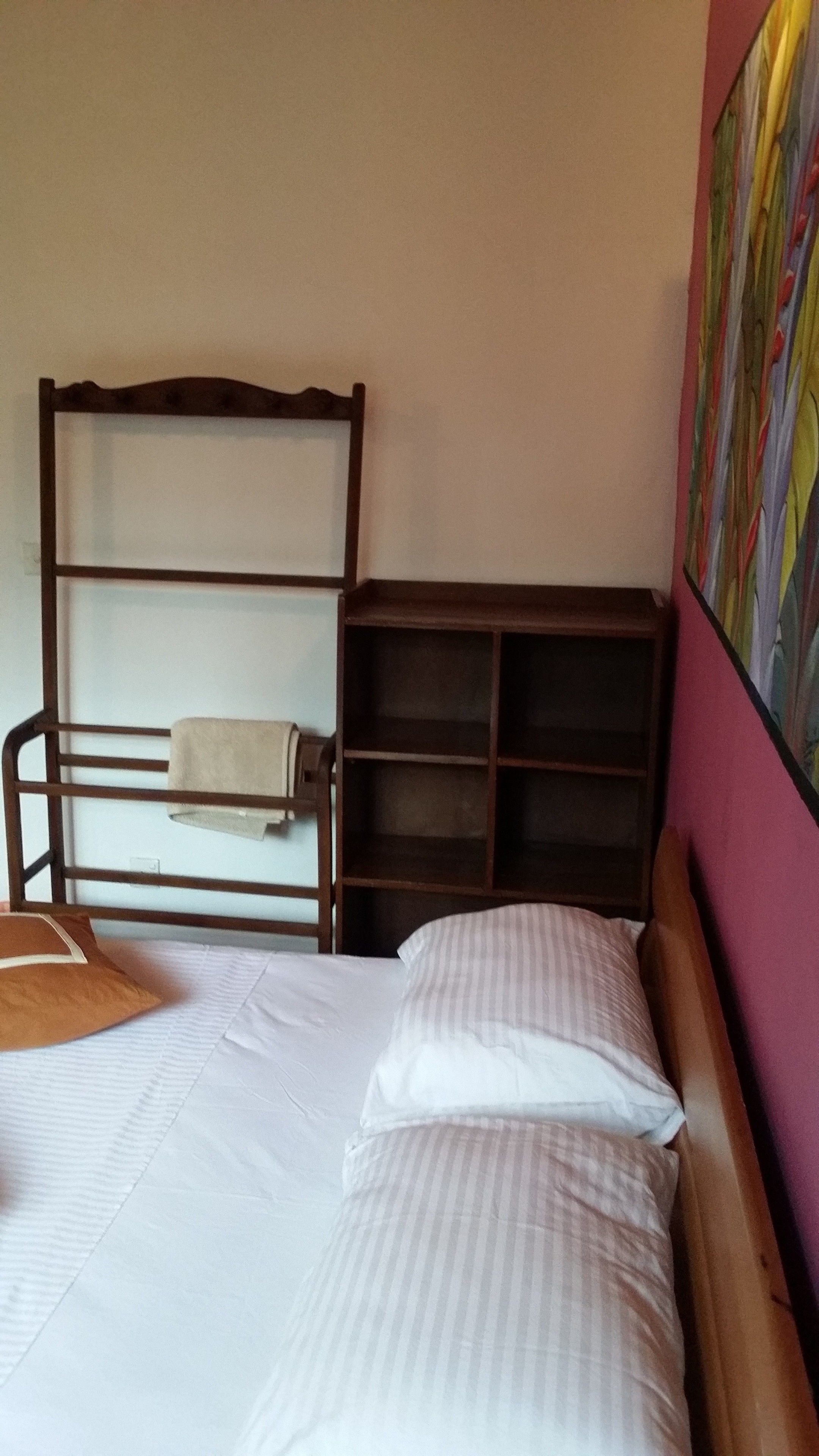 Un lit simple avec une tête de lit en bois et une petite étagère à côté.
